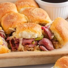 Close-up of a Philly cheesesteak slider showing tender roast beef, peppers, onions, and melted cheese inside soft toasted rolls.