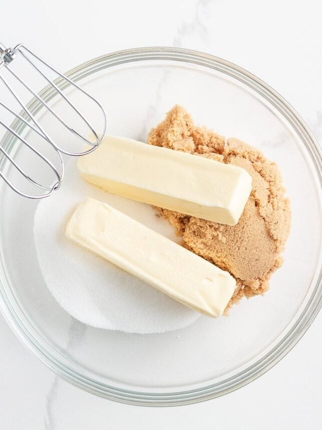 Softened butter, brown sugar and granulated sugar in a mixing bowl before creaming with electric beaters.