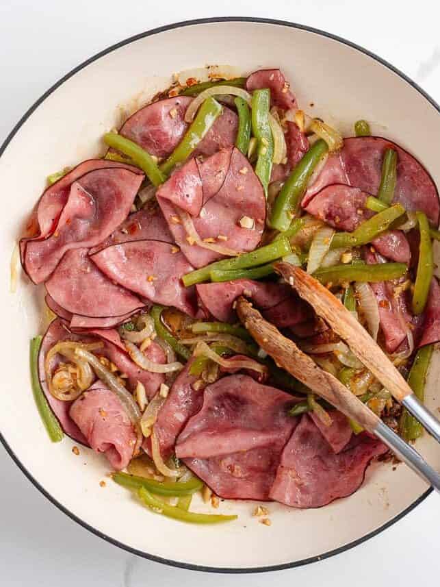 Philly cheesesteak sliders made with Hawaiian rolls stuffed with roast beef, sautéed peppers and onions, and melty cheese. A crowd-pleasing mini version of the classic! Skillet filled with sautéed roast beef, green peppers, onions, and garlic for Philly cheesesteak slider filling.