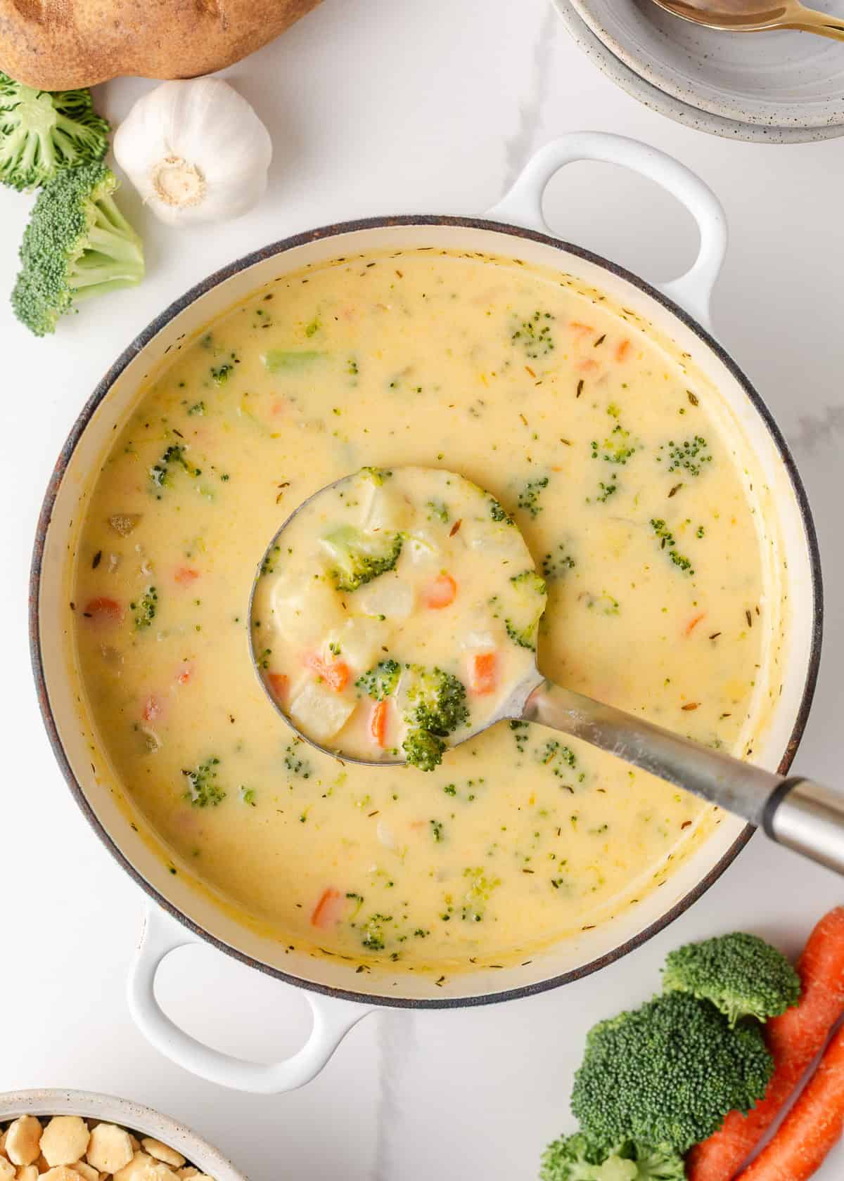 Comforting, easy to make, and packed with flavor, a bowl of this broccoli cheese and potato soup is perfect for cozy dinners! Broccoli cheese and potato soup cooking in a large pot with chunks of potato, carrot, and broccoli.