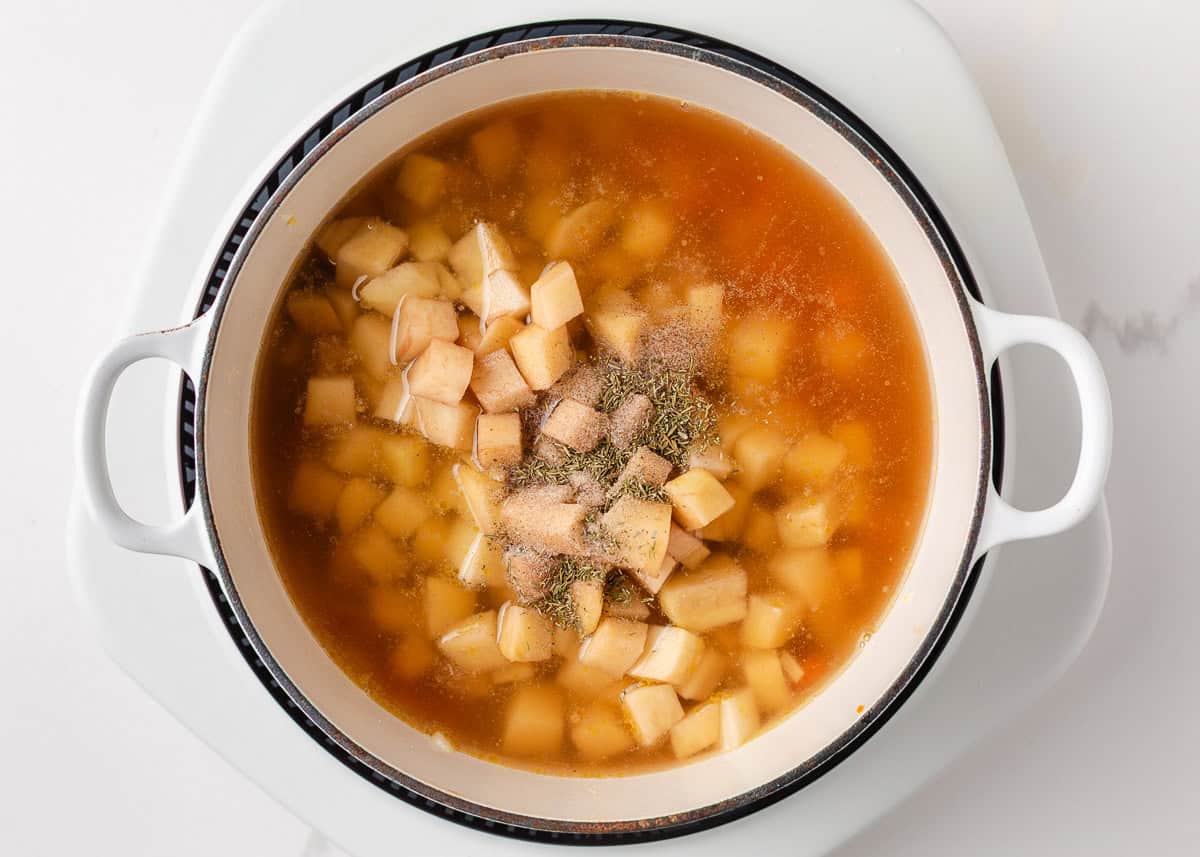 Comforting, easy to make, and packed with flavor, a bowl of this broccoli cheese and potato soup is perfect for cozy dinners! Diced potatoes simmering in broth with seasonings for broccoli cheese and potato soup.