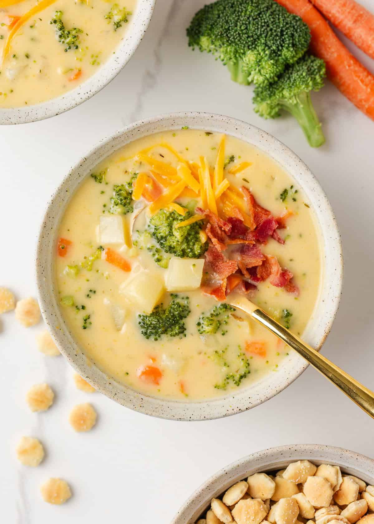 Comforting, easy to make, and packed with flavor, a bowl of this broccoli cheese and potato soup is perfect for cozy dinners! Bowl of broccoli cheese and potato soup topped with shredded cheddar cheese and crispy bacon.