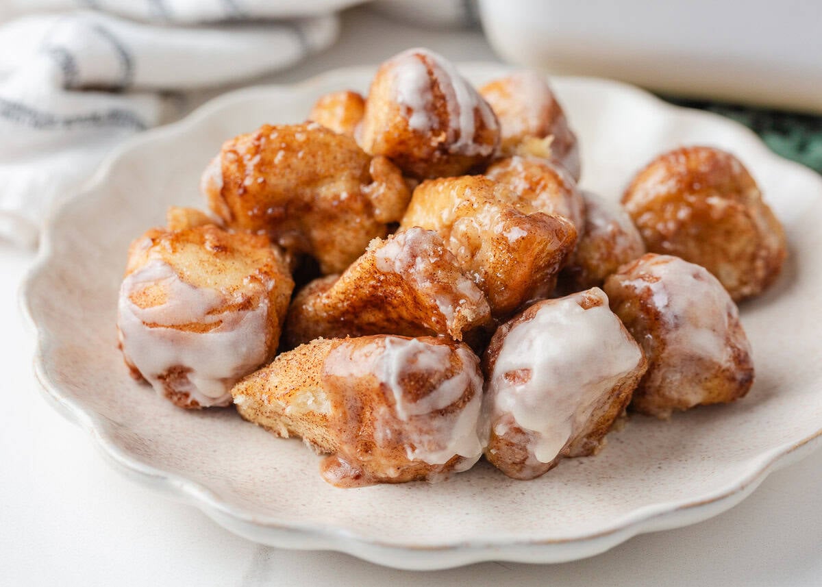 These easy cinnamon roll bites deliver soft, fluffy cinnamon sugar goodness in a bite-sized treat made with ready-made frozen dough. They're perfectly gooey for a sweet treat! Gooey cinnamon roll bites coated in vanilla glaze on a serving plate.