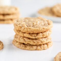 Three soft and chewy oatmeal cookies stacked on each other with more cookies in background.