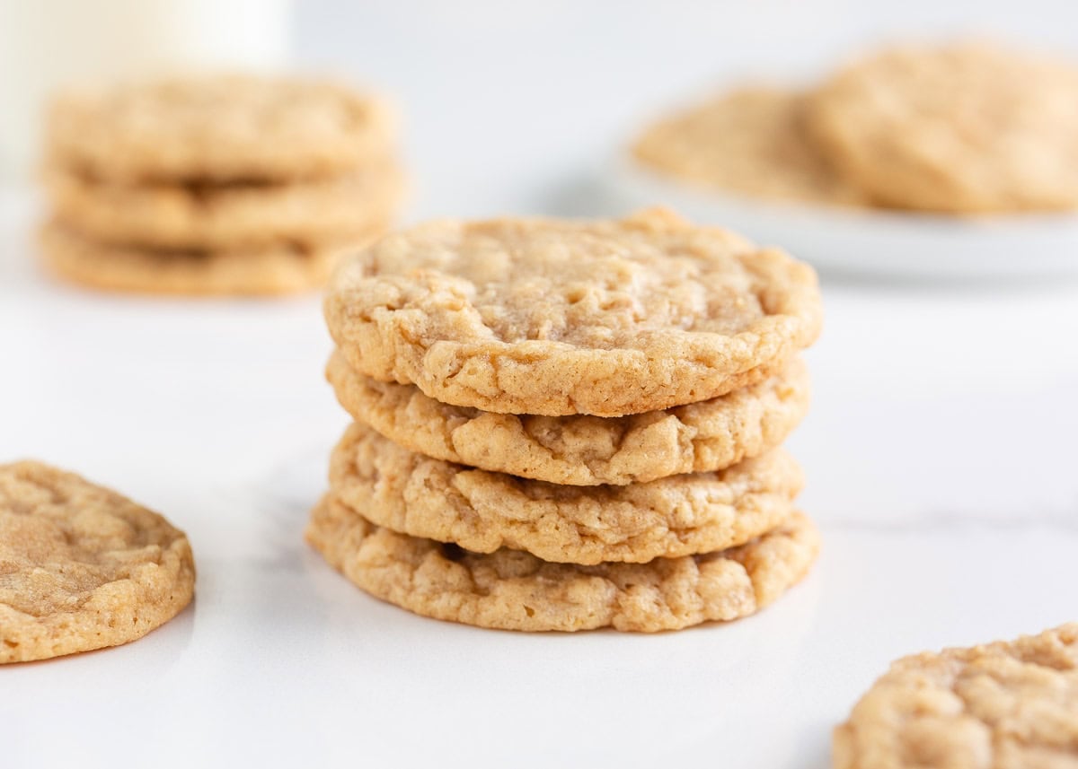 Three soft and chewy oatmeal cookies stacked on each other with more cookies in background.