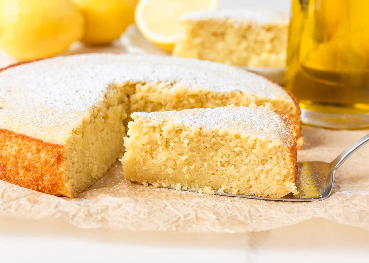 This lemon olive oil cake is sunshine in dessert form, with a light, tender crumb and bright lemon flavor in every bite. Elegant yet simple, it’s an effortless cake to make. Moist lemon olive oil cake slice showing tender crumb, dusted with powdered sugar.