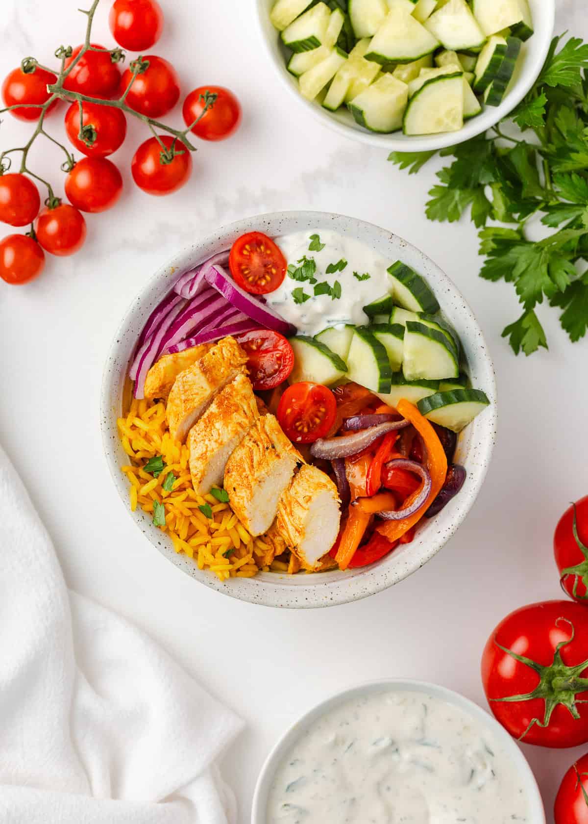 Colorful, fresh, and customizable, these chicken shawarma bowls are packed with bold spices, tender chicken, and all your favorite toppings. Chicken shawarma bowls with sliced spiced chicken, yellow rice, cucumbers, tomatoes, red onion, and creamy sauce.
