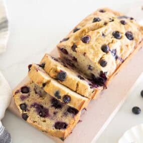 Blueberry banana bread sliced to show berries throughout the crumb.