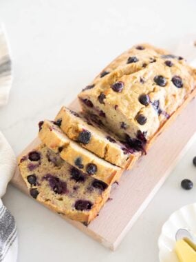 Blueberry banana bread sliced to show berries throughout the crumb.