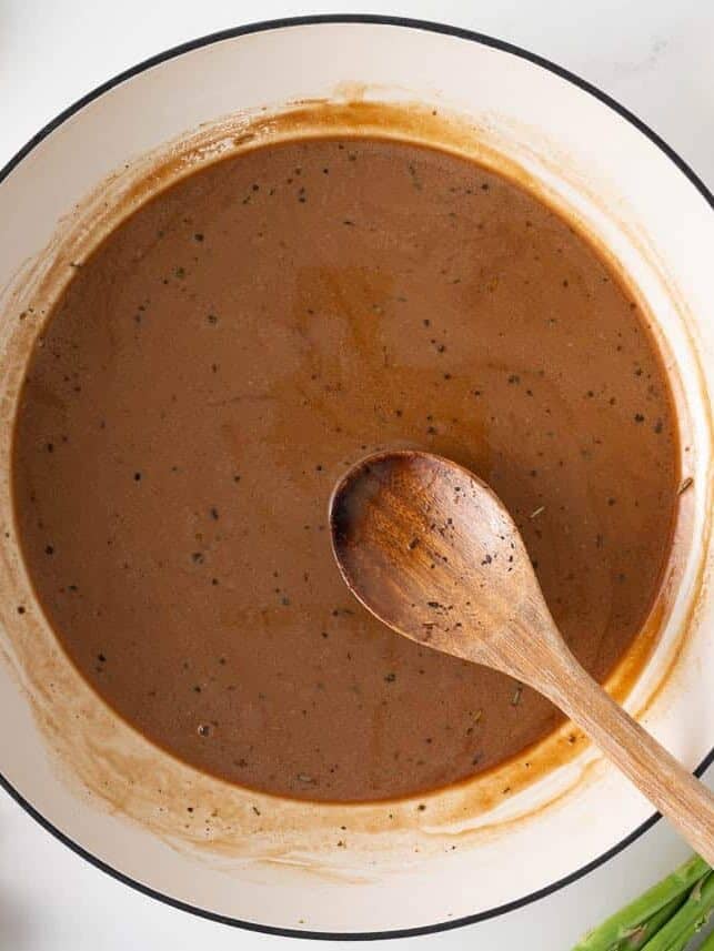 Madeira wine sauce simmering in a skillet until thickened and smooth.