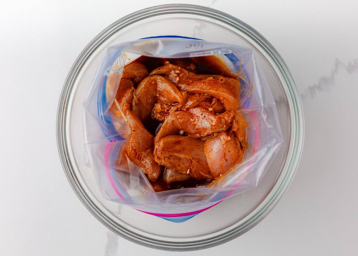 Colorful, fresh, and customizable, these chicken shawarma bowls are packed with bold spices, tender chicken, and all your favorite toppings. Chicken marinating with shawarma spices and lemon juice in a zip-top bag.