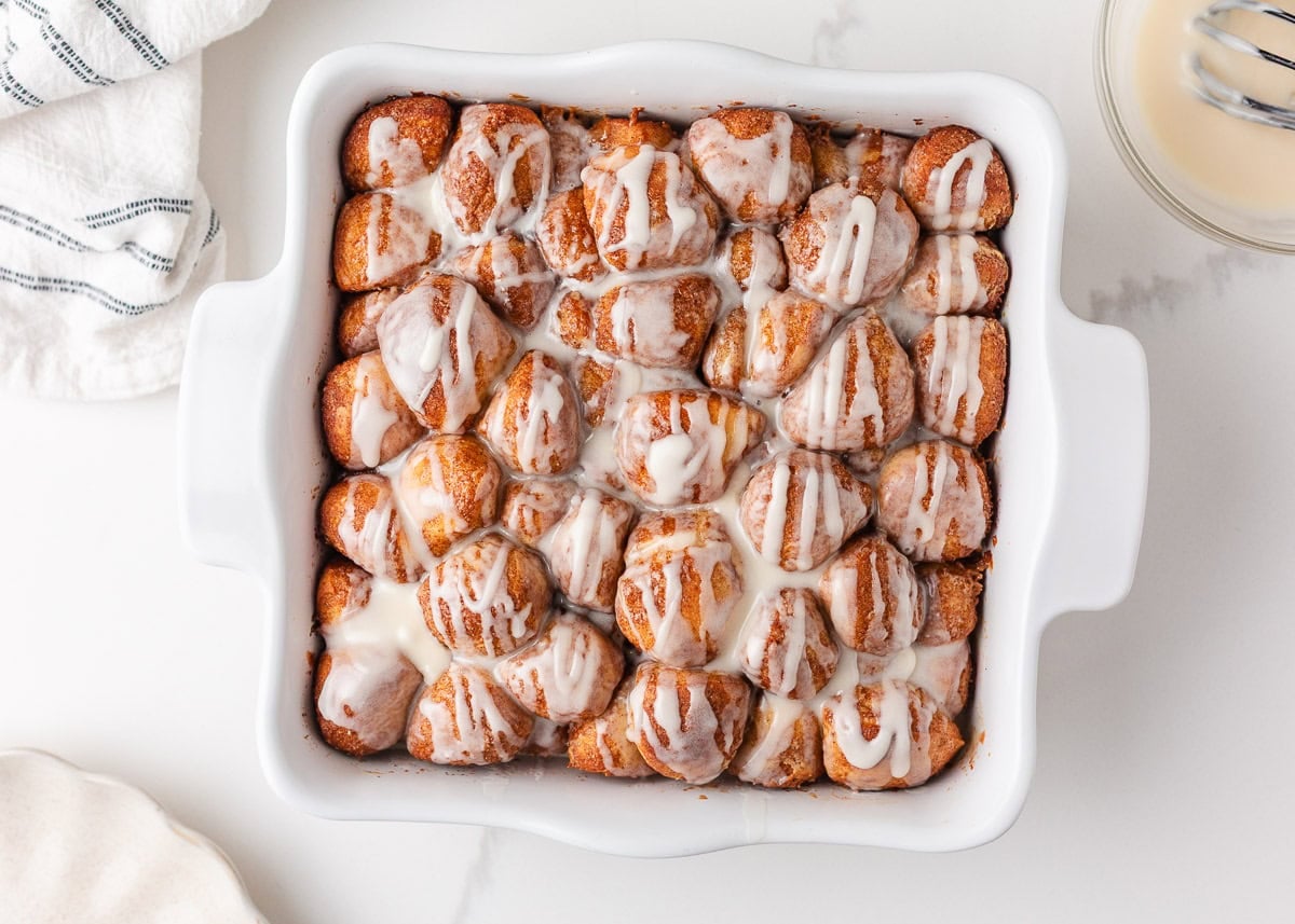 These easy cinnamon roll bites deliver soft, fluffy cinnamon sugar goodness in a bite-sized treat made with ready-made frozen dough. They're perfectly gooey for a sweet treat! Gooey cinnamon roll bites baked in a square dish with vanilla icing.