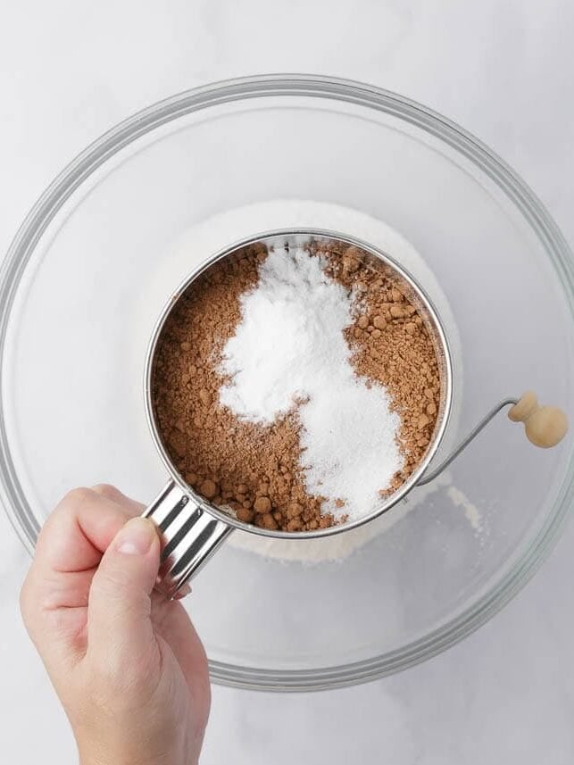 Sifted flour, sugar, cocoa powder, baking soda, and salt combined in a large bowl for German chocolate cake.