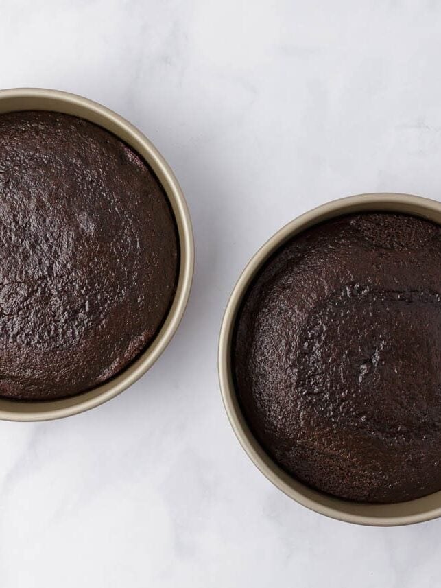 Two baked German chocolate cake layers cooling in round cake pans.