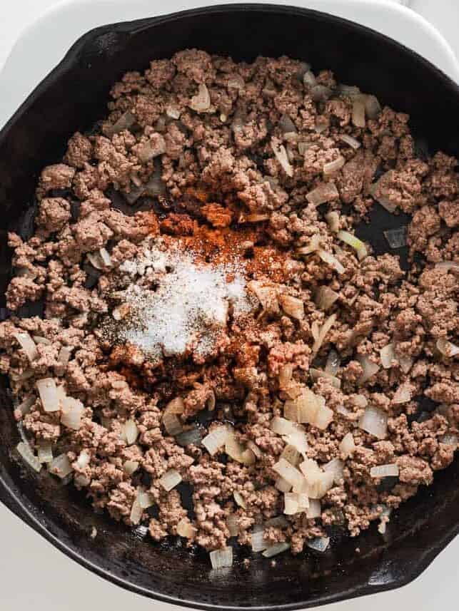 Ground beef cooked with onions and seasonings in a skillet.