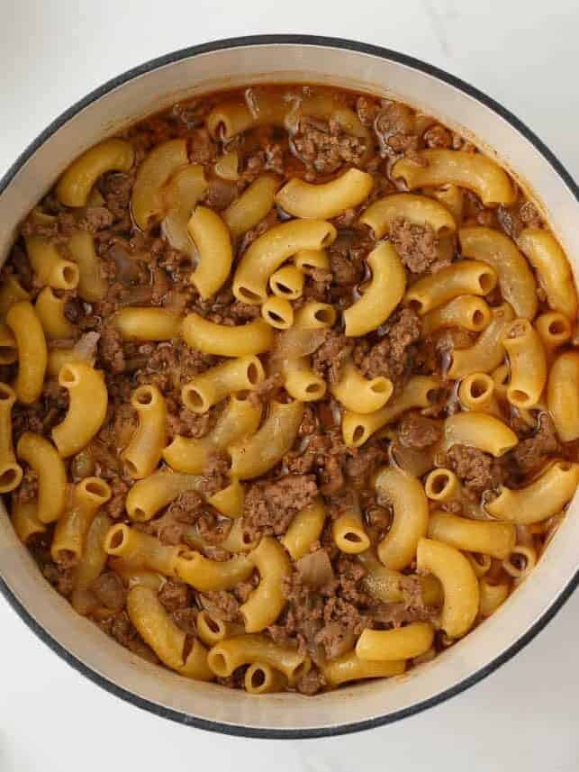 Elbow macaroni and ground beef simmering together in a pot before adding cheese.