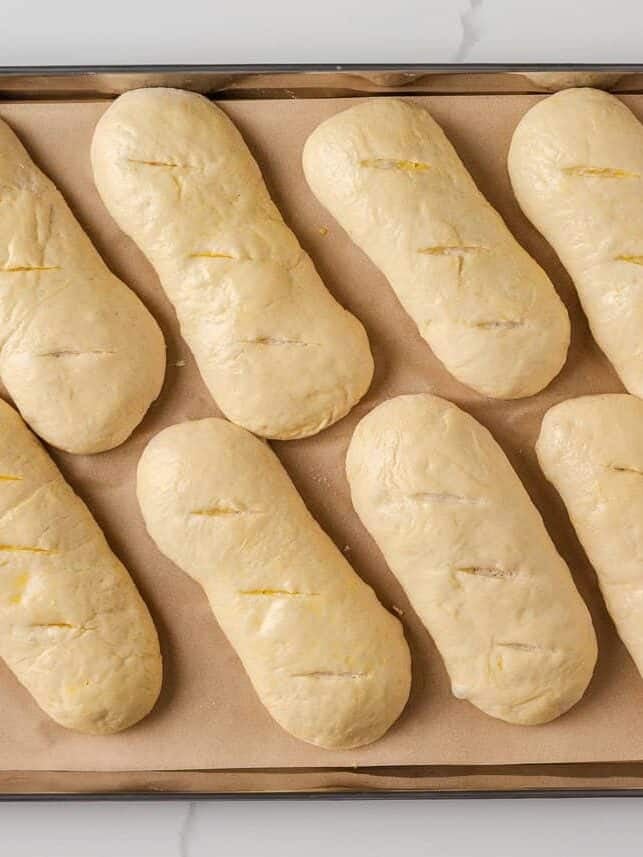 Soft on the inside with a golden, chewy crust, these homemade hoagie rolls are easy to make and instantly upgrade your favorite subs and sandwiches. Hoagie rolls brushed with egg wash and scored before baking.