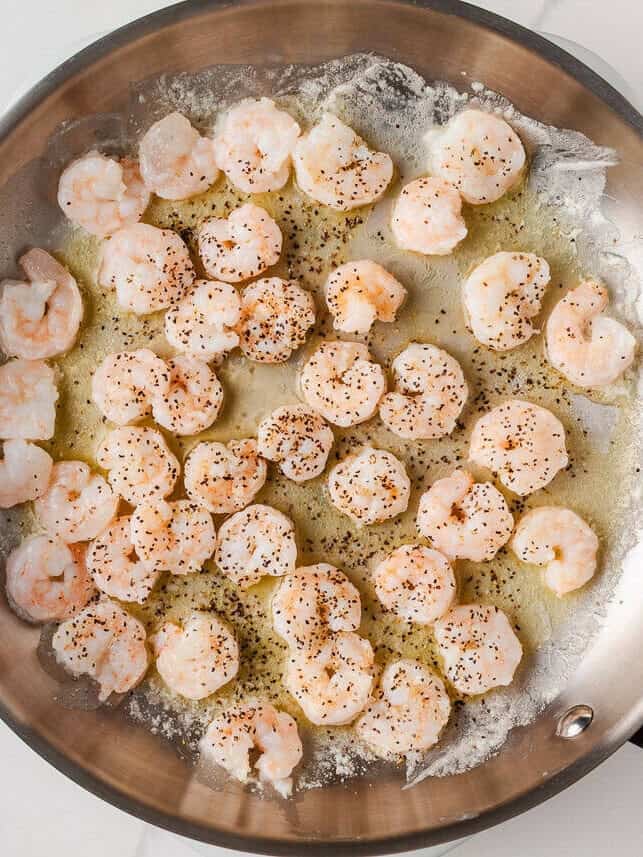 Just a few simple ingredients come together to create this rich and creamy shrimp fettuccine alfredo, ready in 25 minutes! Shrimp sautéing in butter and garlic in a skillet for shrimp alfredo.