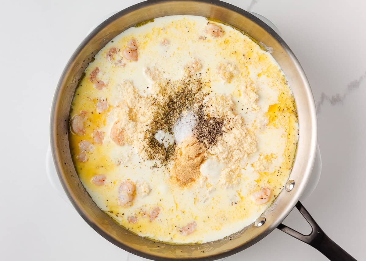 Just a few simple ingredients come together to create this rich and creamy shrimp fettuccine alfredo, ready in 25 minutes! Heavy cream, butter, Parmesan cheese, and seasonings simmering to make alfredo sauce.