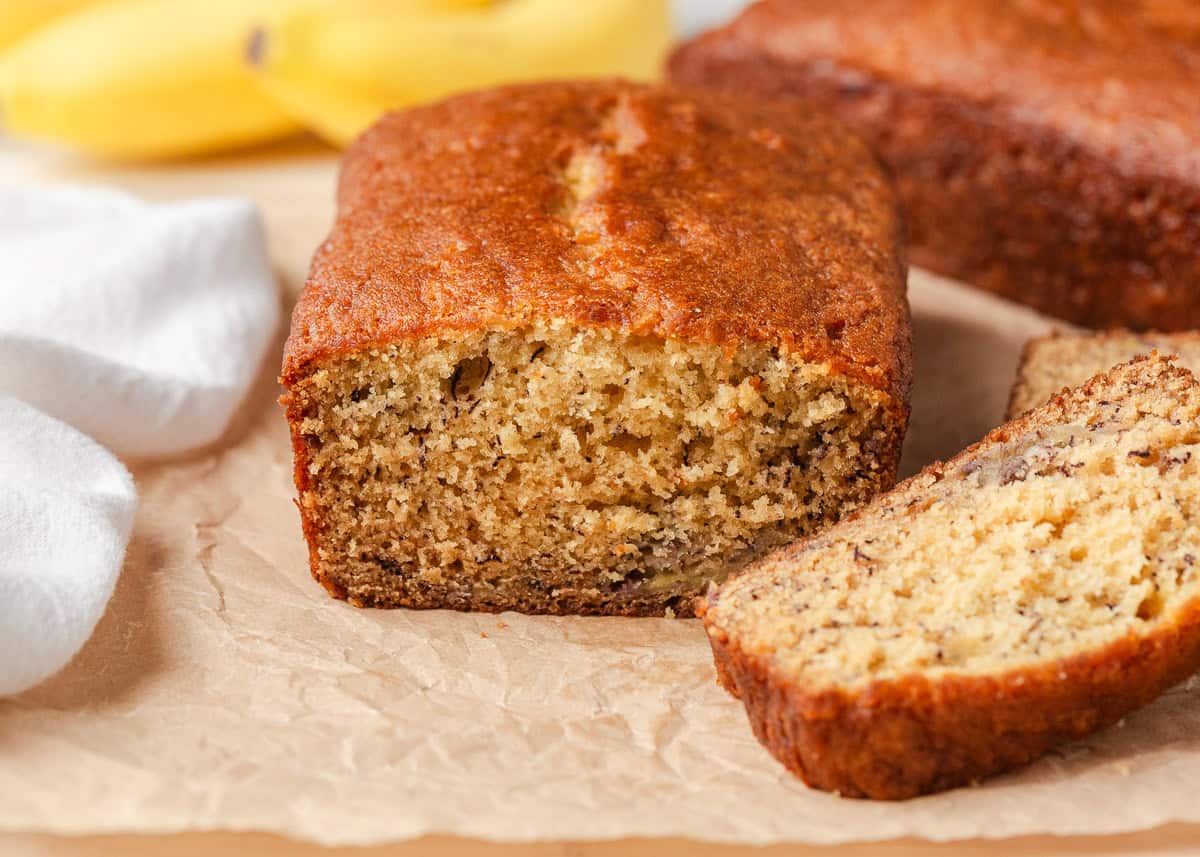 This sour cream banana bread is extra soft, moist, and full of flavor thanks to one simple ingredient. It’s an easy recipe and the perfect way to use up overripe bananas. End of a sour cream banana bread loaf sliced showing a moist, tender crumb.
