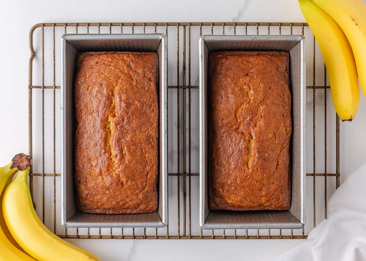 This sour cream banana bread is extra soft, moist, and full of flavor thanks to one simple ingredient. It’s an easy recipe and the perfect way to use up overripe bananas. Banana sour cream bread baked until golden and cooling in loaf pans.