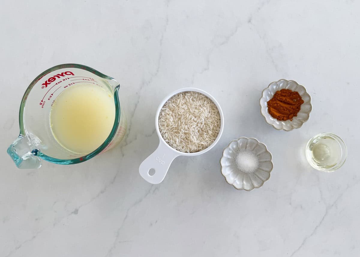 This easy yellow rice is cooked on the stovetop with chicken broth and turmeric for a fluffy, flavorful side dish recipe that elevates any meal and is ready in only 25 minutes! Ingredients for yellow rice including white rice, chicken broth, turmeric, olive oil, and salt.