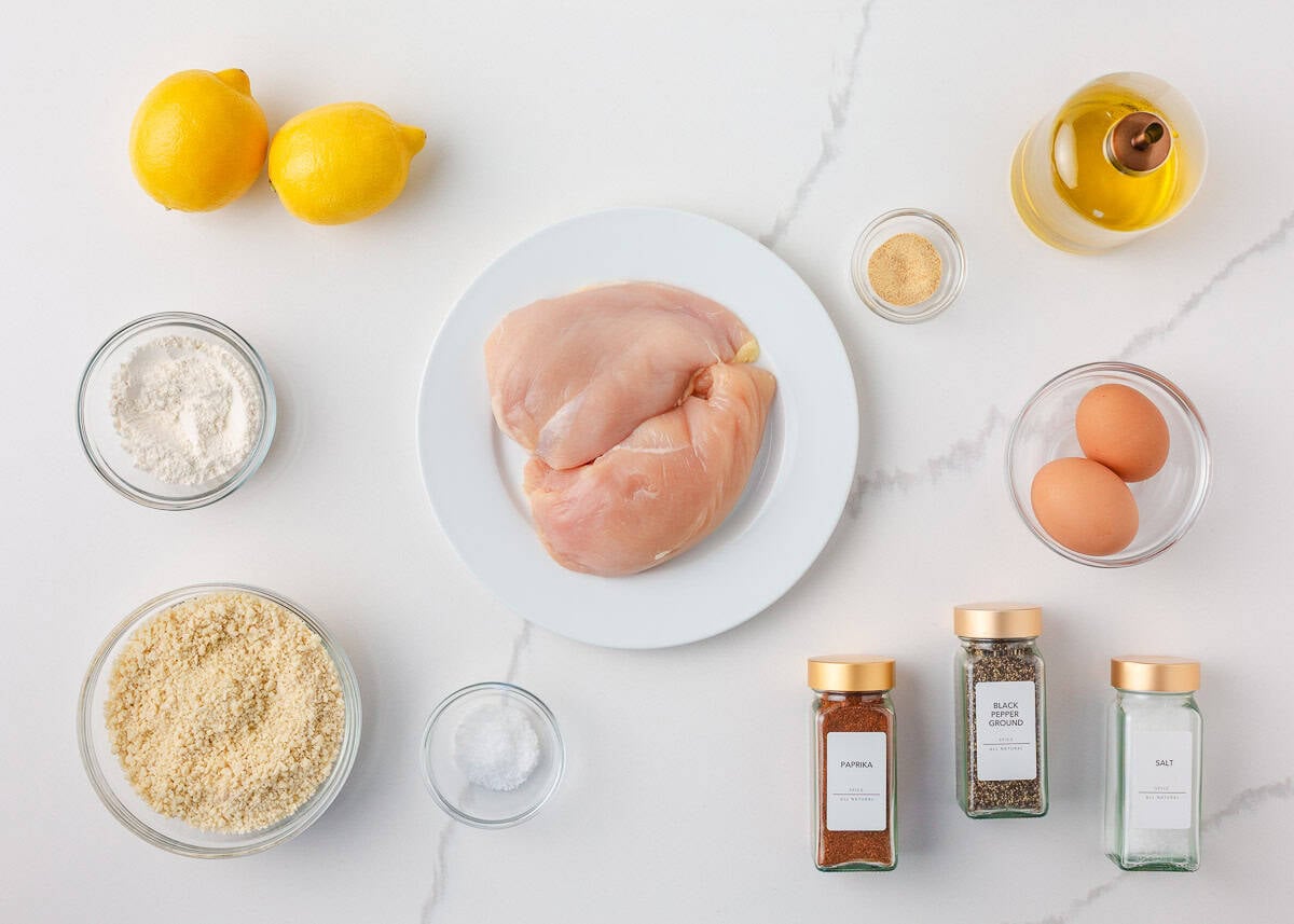 This chicken schnitzel is coated in seasoned breadcrumbs and pan fried until perfectly crispy, then finished with a squeeze of lemon. Thin, juicy, and ready in 30 minutes! Ingredients for chicken schnitzel including chicken breasts, panko breadcrumbs, eggs, flour, olive oil, lemon, and seasonings.