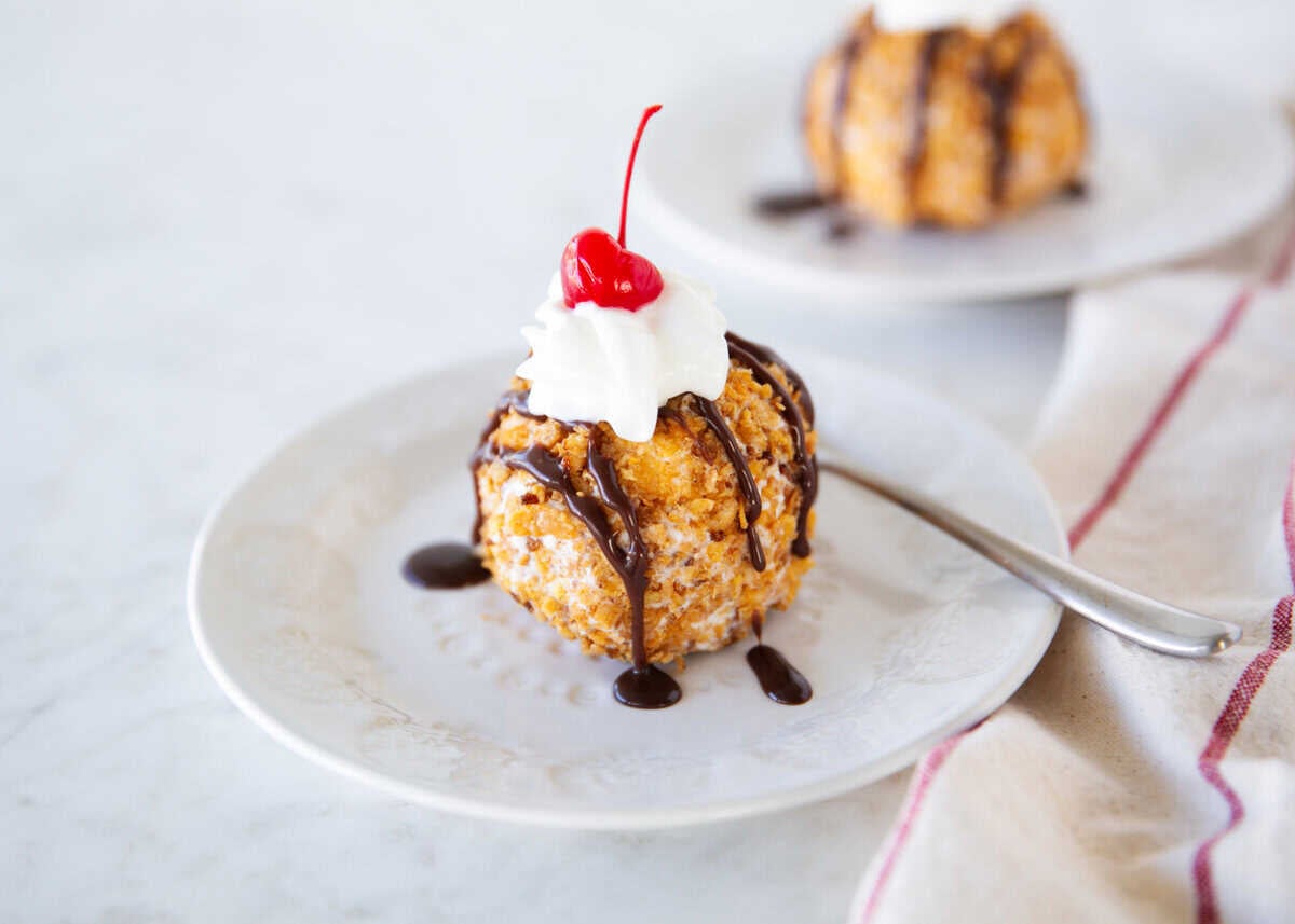 Fried ice cream topped with whipped cream, chocolate sauce, and a maraschino cherry.