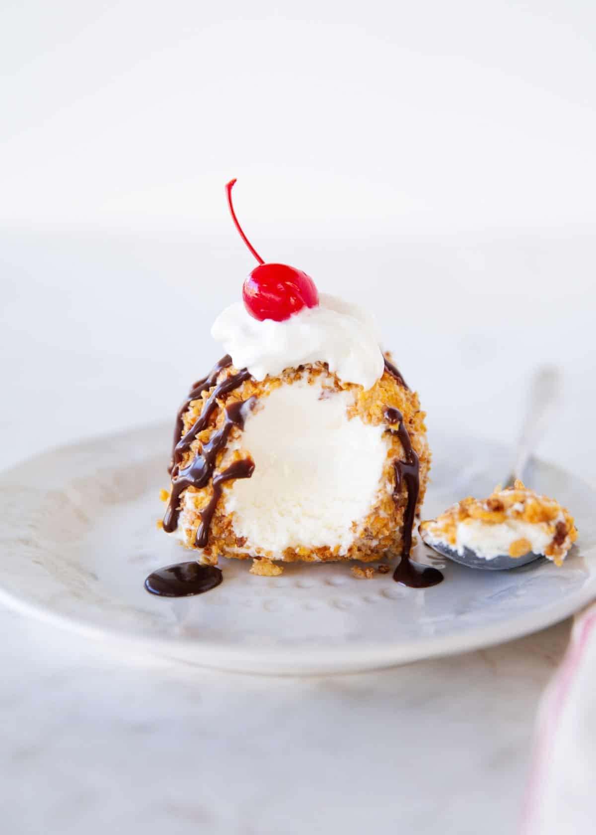 Cut open fried ice cream showing creamy vanilla center and crispy cinnamon cereal coating.