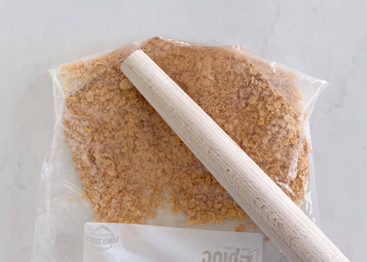 This fried ice cream recipe is made without deep frying, so it’s easy, mess-free, and just as crunchy as your favorite Mexican restaurant dessert. Crushing frosted flakes in a zip-top bag with a rolling pin for fried ice cream coating.