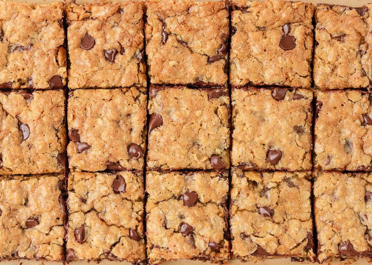 Loaded with oats, brown sugar, and melty chocolate chips, these oatmeal cookie bars are thick, chewy, and made in a single batch. No cookie scoop required! Freshly baked oatmeal cookie bars cut into squares with melted chocolate chips throughout.