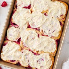 Pan of raspberry sweet rolls baked until golden and topped with cream cheese frosting.