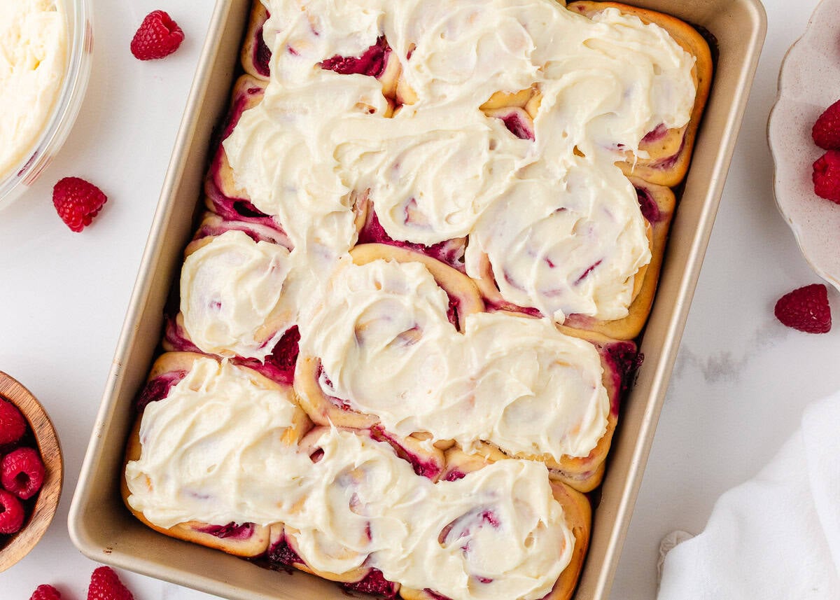 Pan of raspberry sweet rolls baked until golden and topped with cream cheese frosting.