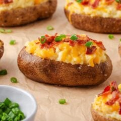 Cheesy twice baked potatoes with bacon and green onions arranged on parchment paper, ready to serve.