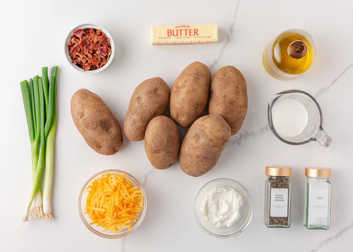 A crowd pleasing side dish these twice baked potatoes are made with baked potato shells stuffed with creamy mashed potatoes then topped with cheese! Ingredients for twice baked potatoes including russet potatoes, shredded cheddar cheese, bacon, sour cream, butter, milk, olive oil, and green onions.
