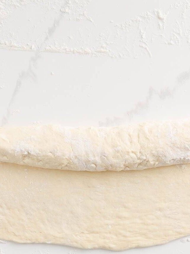 Shaping Italian bread dough into a loaf before the second rise.