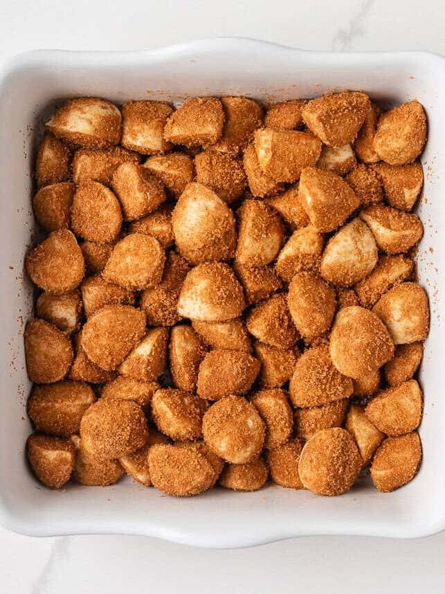These easy cinnamon roll bites deliver soft, fluffy cinnamon sugar goodness in a bite-sized treat made with ready-made frozen dough. They're perfectly gooey for a sweet treat! Unbaked cinnamon roll bites coated in brown sugar and cinnamon in a baking dish.