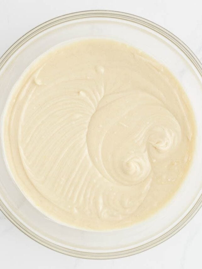 Coconut cupcake batter mixed until smooth in a glass bowl.