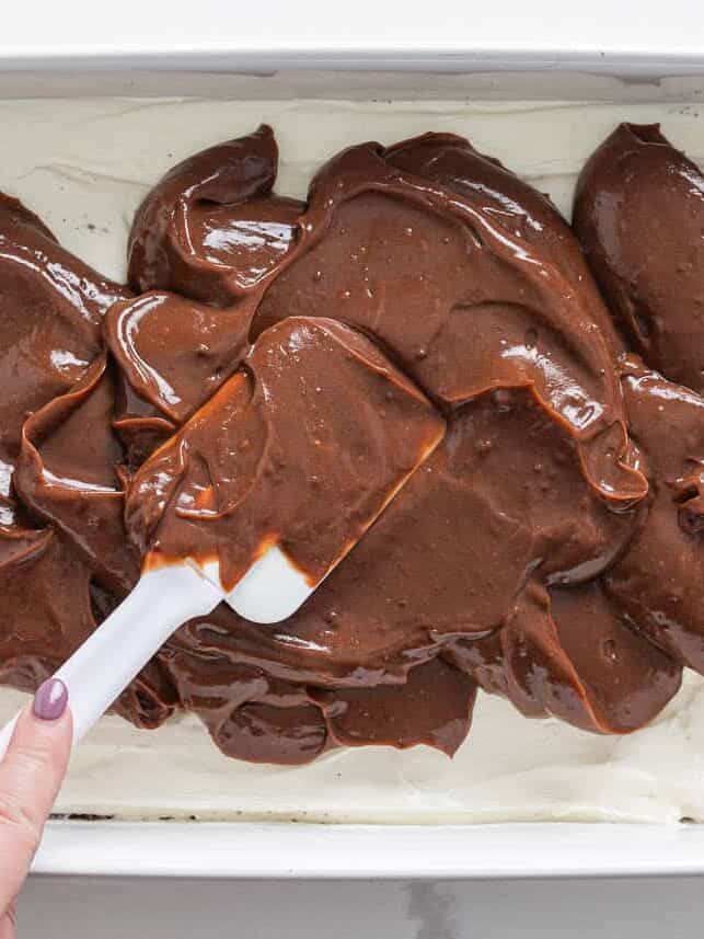 Adding chocolate pudding on top of the cream layer in a 9×13 dish.