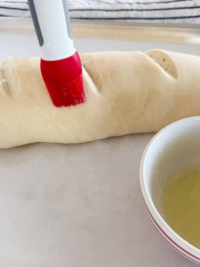 Brushing egg wash over homemade Italian bread dough before baking.