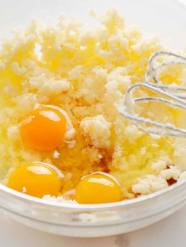 Butter, sugar, eggs, and vanilla being mixed together to make lemon cake batter before adding blueberries.