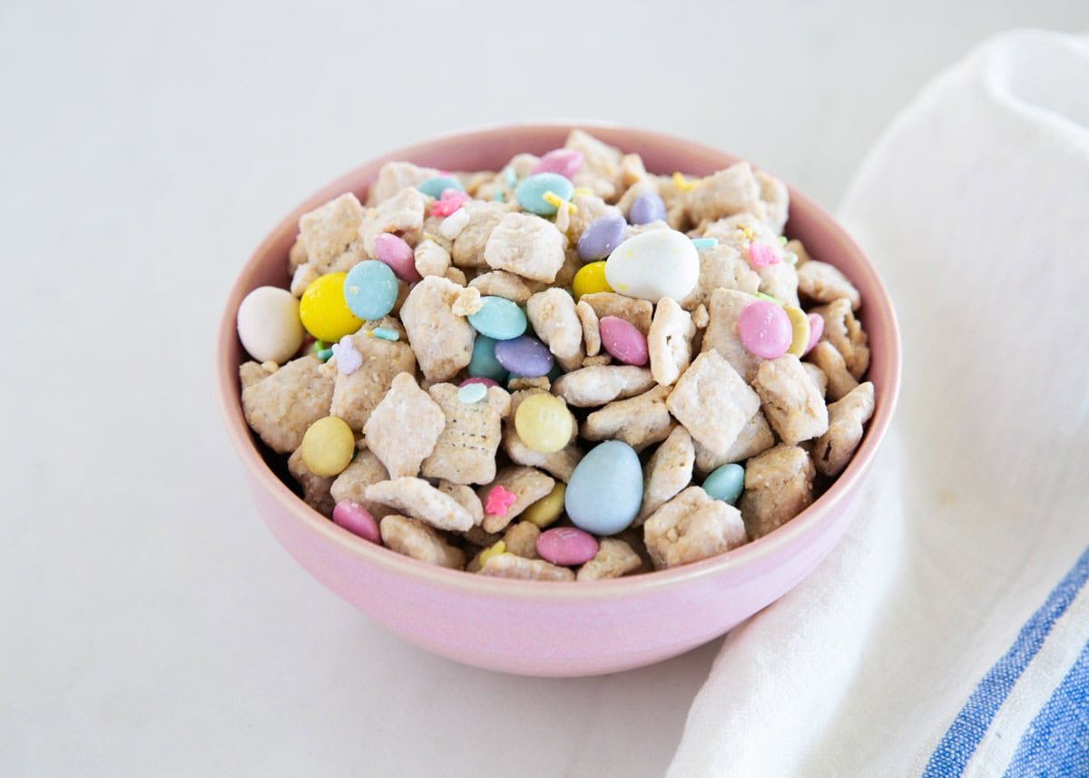 Bowl of Easter puppy chow made with Chex cereal, white chocolate, peanut butter, pastel M&M&rsquo;s, and sprinkles.