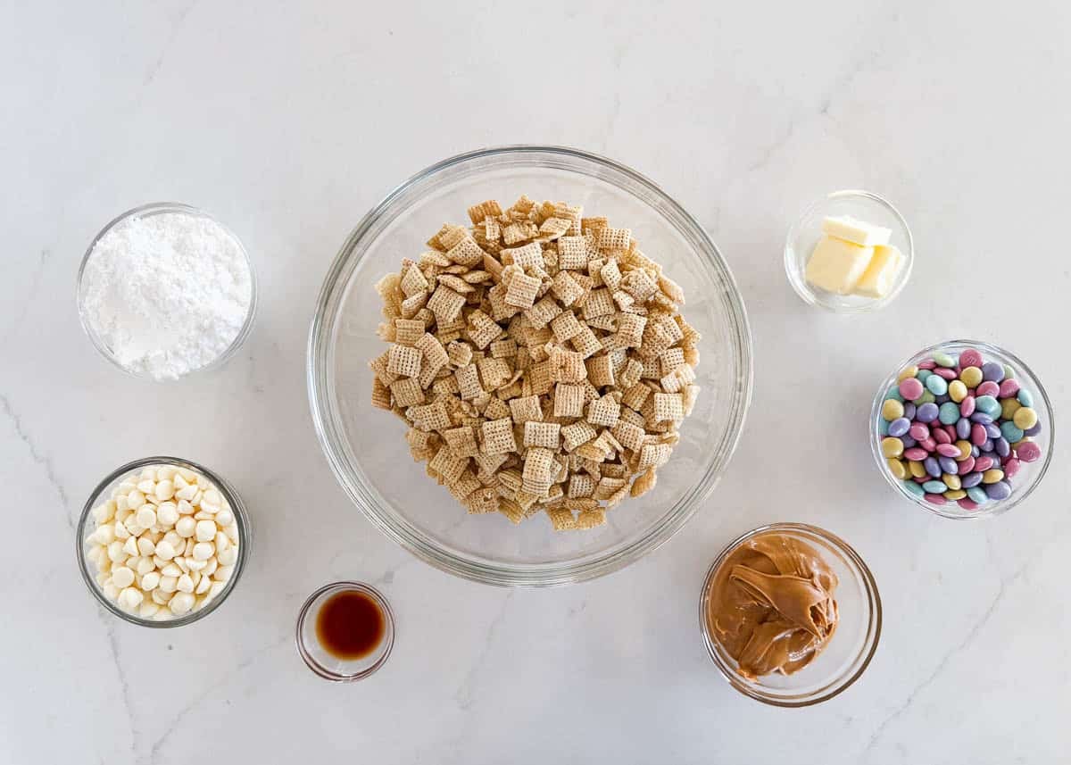 This Easter puppy chow is a quick no-bake treat for spring! Chex cereal is coated in white chocolate and peanut butter, then tossed with powdered sugar and pastel M&M’s. Ingredients for Easter puppy chow including Rice Chex cereal, white chocolate chips, peanut butter, butter, vanilla, powdered sugar, and pastel M&M’s.