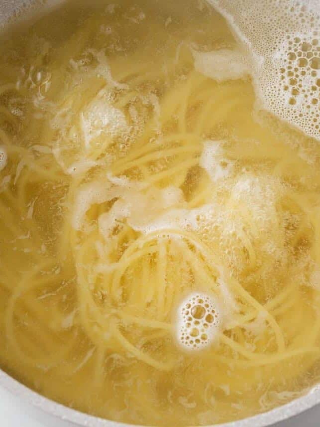 Spaghetti noodles boiling in a pot of water.