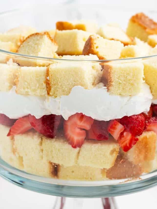 Whipped cream spread over the first strawberry and pound cake layer in a trifle dish.