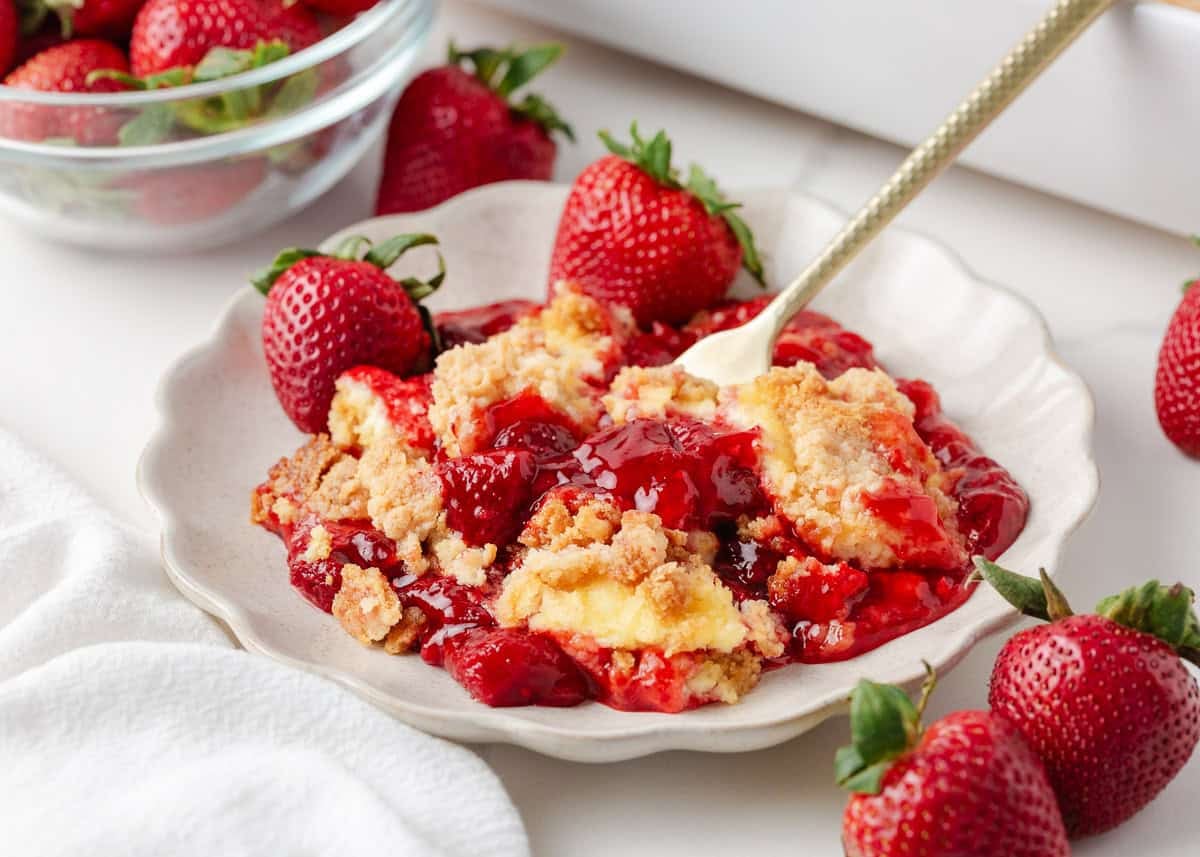 Close up of strawberry cheesecake dump cake with creamy cheesecake layer and juicy strawberry filling.
