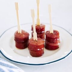 Brown sugar kielbasa bites served on a white plate with appetizer picks.