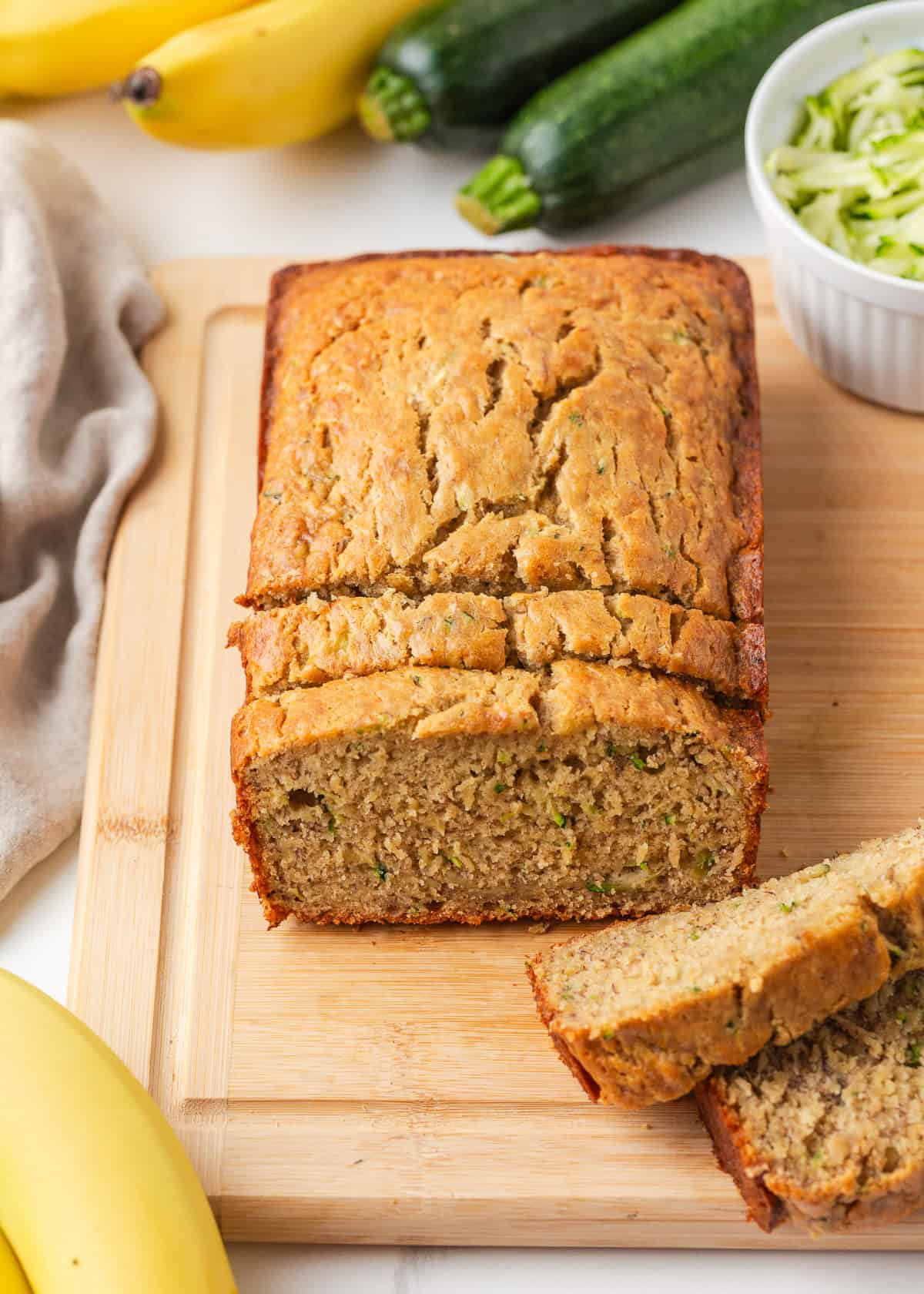 Moist, tender, and packed with flavor, this zucchini banana bread is a delicious way to use up ripe bananas and fresh zucchini in one easy loaf! Moist zucchini banana bread sliced on a cutting board showing a tender crumb.