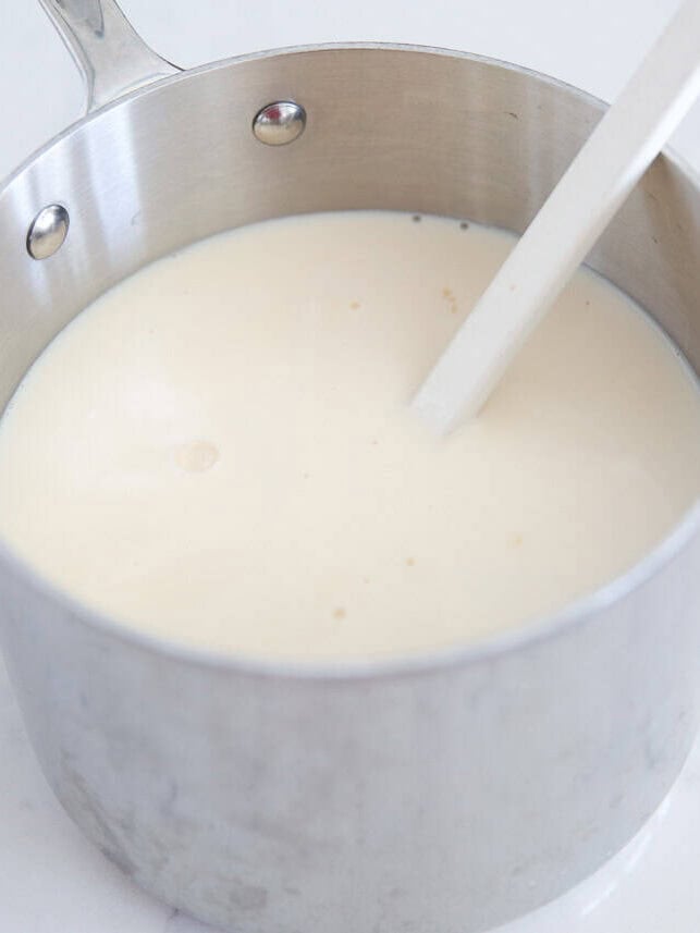 Three milks being stirred together in a saucepan to make Mexican rice pudding.