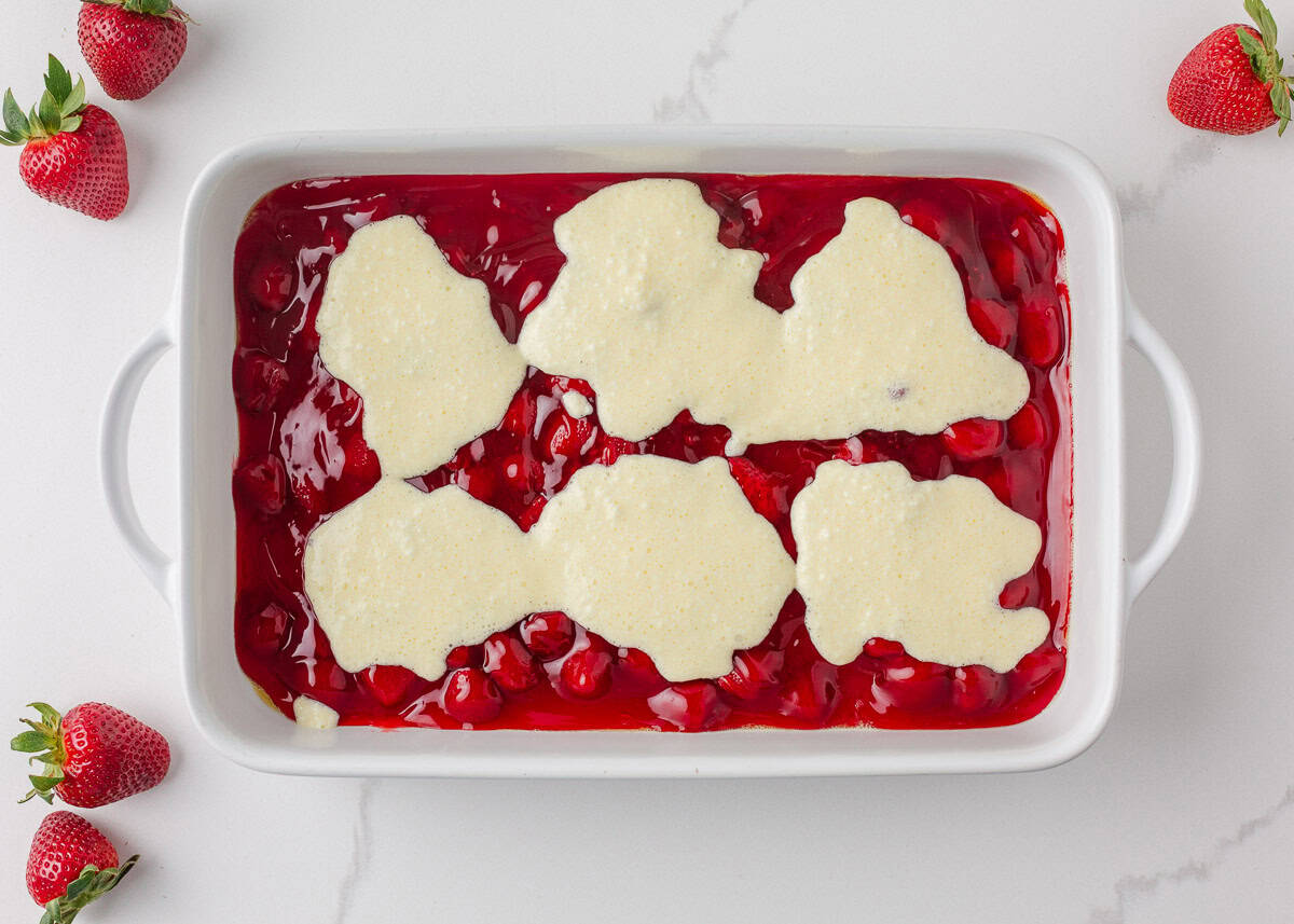 Cream cheese mixture spooned over strawberry pie filling in baking dish.
